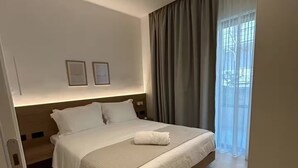Ein modernes Hotelzimmer mit einem großen Bett, einem hölzernen Kopfteil und einem Fenster mit Vorhängen.