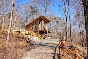 A cabin with a wooden exterior, a porch, and a staircase leading to the entrance.