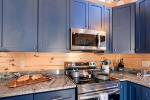 A kitchen with blue cabinets, a microwave, an oven, and a granite countertop.