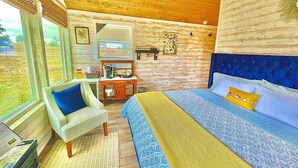 Een slaapkamer met een bed, een stoel, een bureau en een raam.