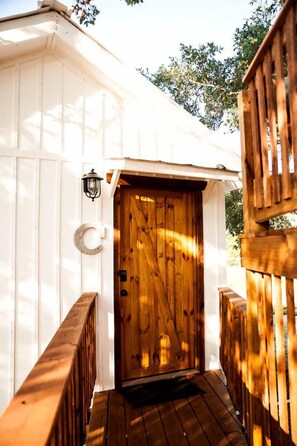 A wooden deck with a wooden door and a lantern on the wall.