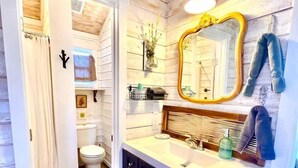 Een badkamer met een houten vloer, een wit wastafelmeubel met spiegel en een toilet.