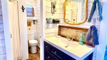 A bathroom with a wooden floor, a white sink with a mirror, and a toilet.