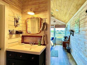 Un interior de madera con un baño que incluye un lavabo, espejo y perchero para toallas.