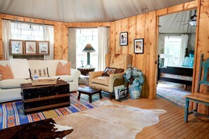 Ein gemütliches Blockhaus-Interieur mit einer Couch, einem Sessel, Holzwänden und einem Bett.