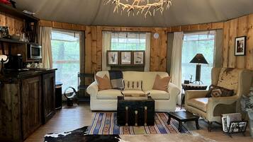 A cozy cabin interior with a wooden interior, a sofa, a chair, a coffee table, and a dining table.