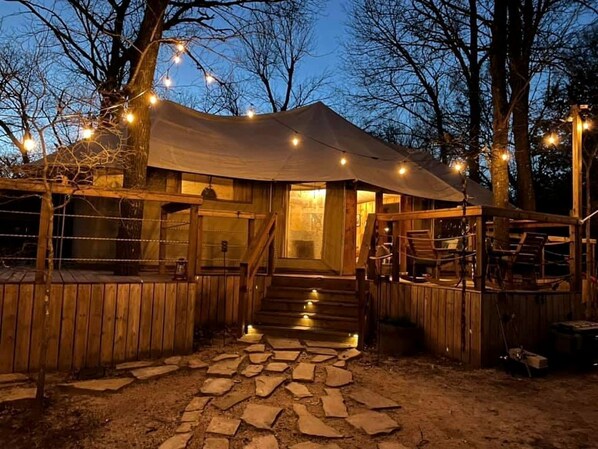 A rustic wooden cabin with a stone pathway leading to the entrance, surrounded by trees.