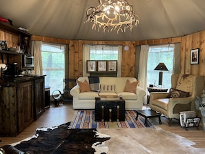 L’intérieur chaleureux d’un chalet, avec un décor en bois, un canapé, un fauteuil, une table basse et une table à manger.