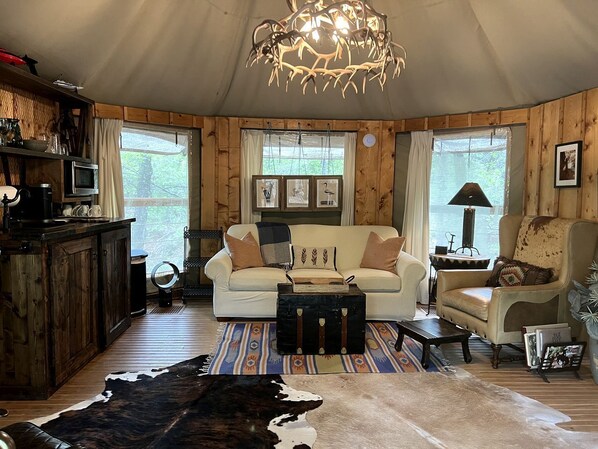 L’intérieur chaleureux d’un chalet, avec un décor en bois, un canapé, un fauteuil, une table basse et une table à manger.