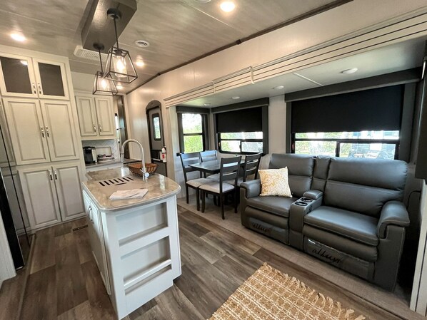 A modern kitchen with white cabinets, a central island, and a dining area with a table and chairs. - Cozy Texas Hill Country Rental for Romantic Getaways in Texas (Dripping Springs)