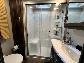 A modern bathroom with a glass-enclosed shower, a white sink, and a toilet. - Cozy Texas Hill Country Rental for Romantic Getaways in Texas (Dripping Springs)