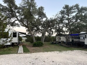 A campsite with RVs, a covered picnic table, and a gravel path. - Cozy Texas Hill Country Rental for Romantic Getaways in Texas (Dripping Springs)