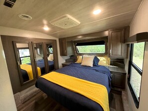 Une chambre à coucher avec un lit, une fenêtre, un miroir et une porte.