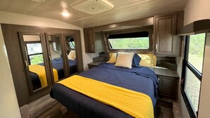 A bedroom with a bed, a window, a mirror, and a door. - Cozy Texas Hill Country Rental for Romantic Getaways in Texas (Dripping Springs)