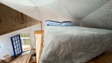 Un dormitorio con cama, almohadas, una ventana y vistas al exterior.