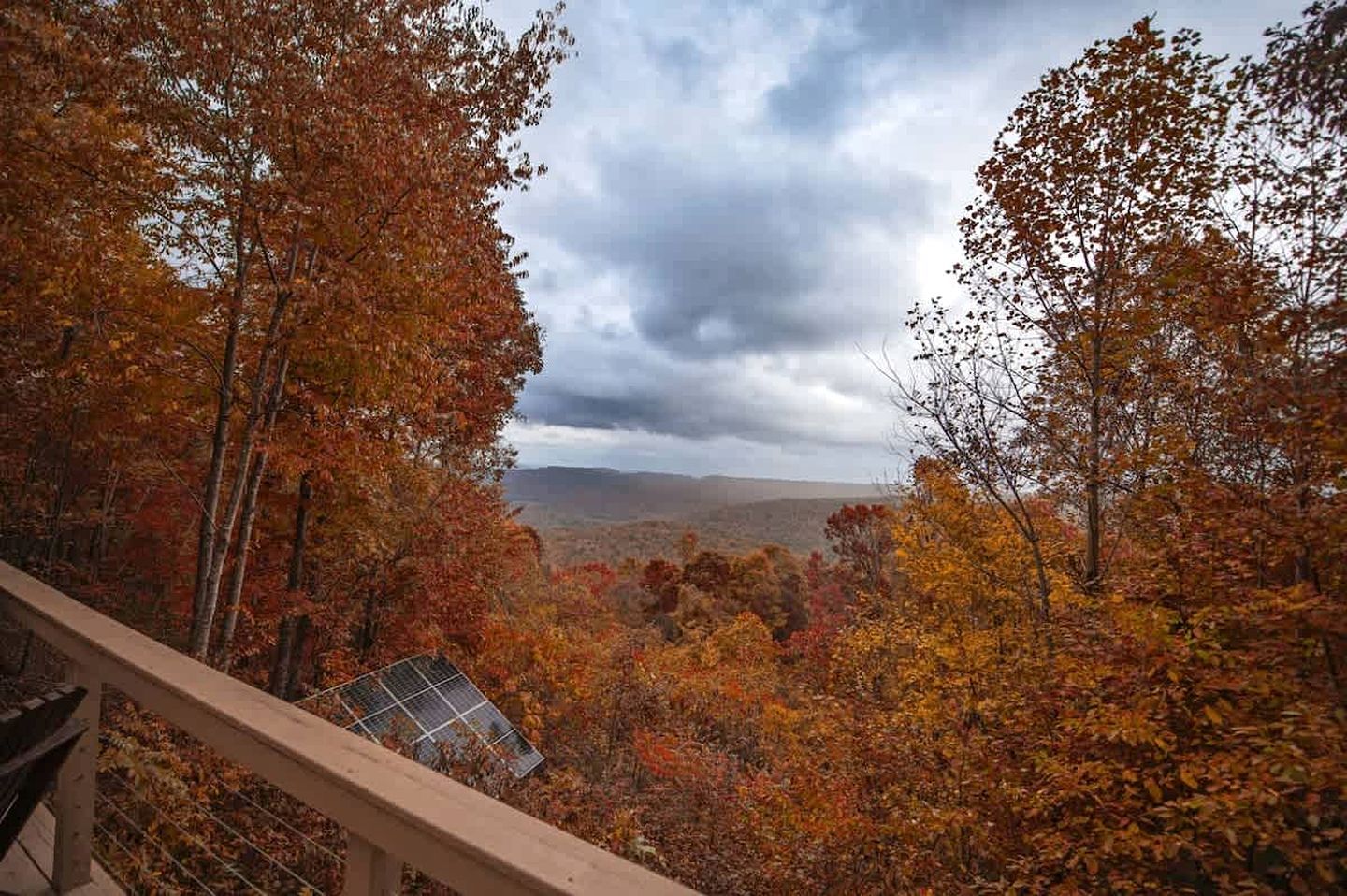 Une vue depuis un balcon, avec un panneau solaire, entouré du feuillage automnal.