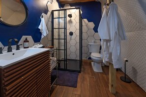 A modern bathroom with a wooden vanity, a glass shower enclosure, a toilet, and a blue and white hexagonal tile wall. - Off-Grid Dome with Private Hot-Tub and Spectacular Sunrise Views in Tennessee (Altamont)
