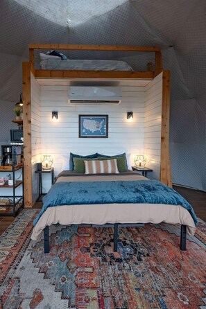 Een slaapkamer met een stapelbed, een groot vloerkleed, een kaart aan de muur en een klein plankje met spullen.