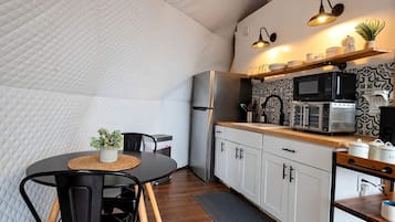 Une cuisine compacte avec un coin repas, un four à micro-ondes et un réfrigérateur.