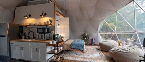 Un espacio habitable acogedor y compacto con kitchenette, una zona de estar cómoda y un ventanal con vistas al exterior.