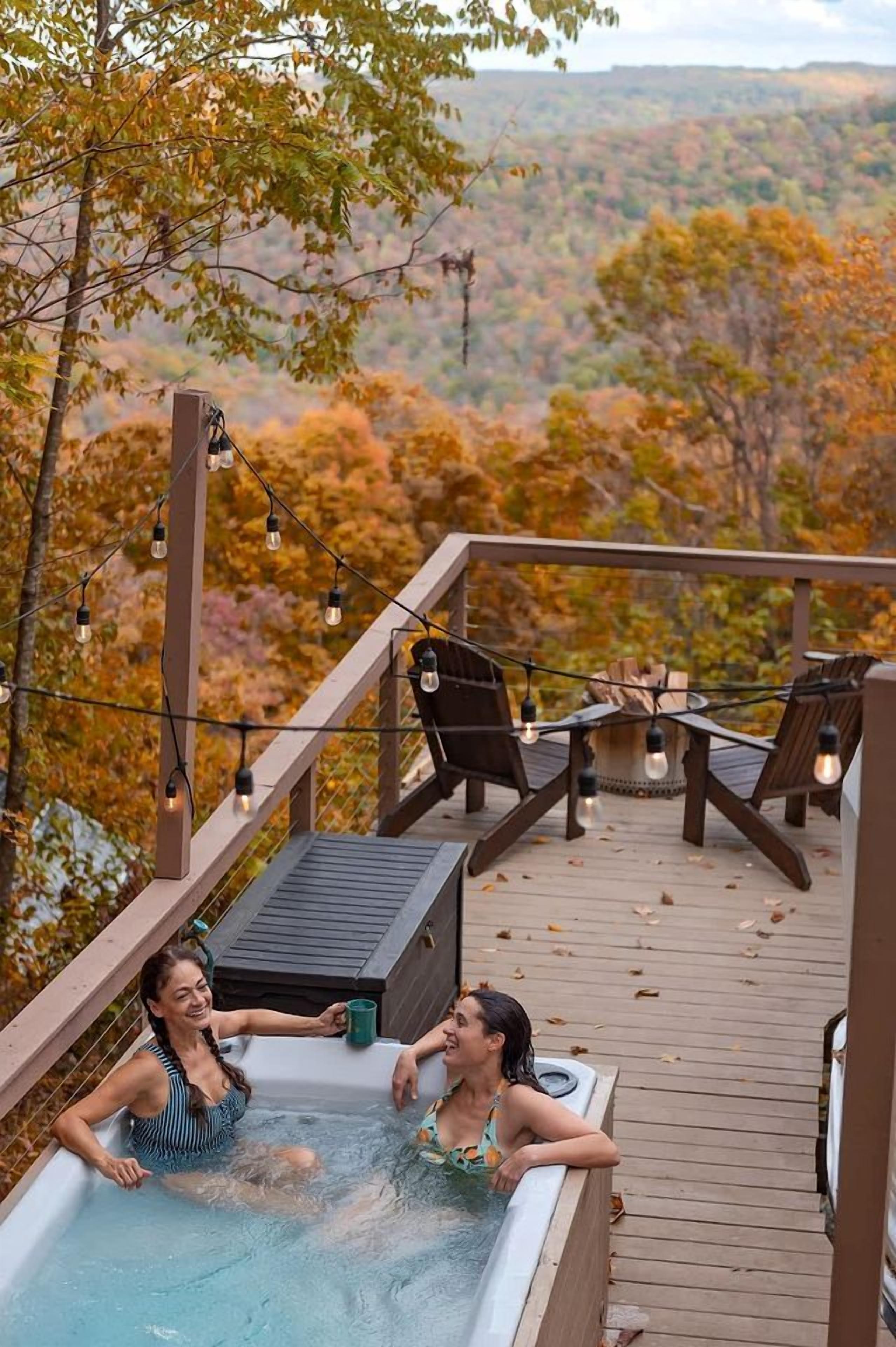 Ein Whirlpool auf einer Holzterrasse mit Blick auf herbstliches Laub.