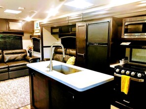 A compact kitchen with a built-in sink, a stove, and a microwave.