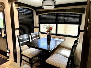 A compact dining area with a table, chairs, and a window with blinds.