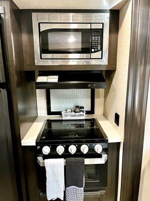 Eine kleine Küche mit Mikrowelle, Herd und Backofen.