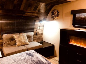 Une pièce chaleureuse avec un canapé, une petite table, une cheminée et des lambris en bois.