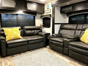 Ein kompaktes Wohnmobil-Interieur mit zwei Ledersofas, einem kleinen Tisch und einem Kamin.