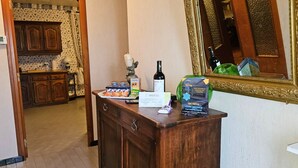 A wooden dresser with a bottle of wine, a box of chocolates, and a card in a hotel room. - L'oustal- Oc Keys- Family home, private garden, close to freeway (Bram)