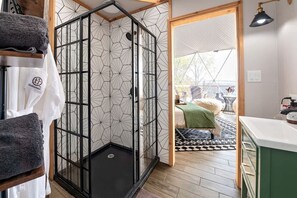 Un baño moderno con cabina de ducha de vidrio, suelo de madera y vistas al exterior.