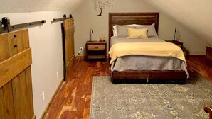 A bedroom with a wooden bed, a nightstand, a dresser, and a wall-mounted tree decoration.