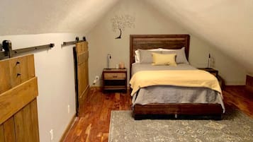 A bedroom with a wooden bed, a nightstand, a dresser, and a wall-mounted tree decoration.
