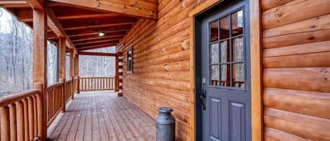 A wooden cabin with a porch, a door, and a window.