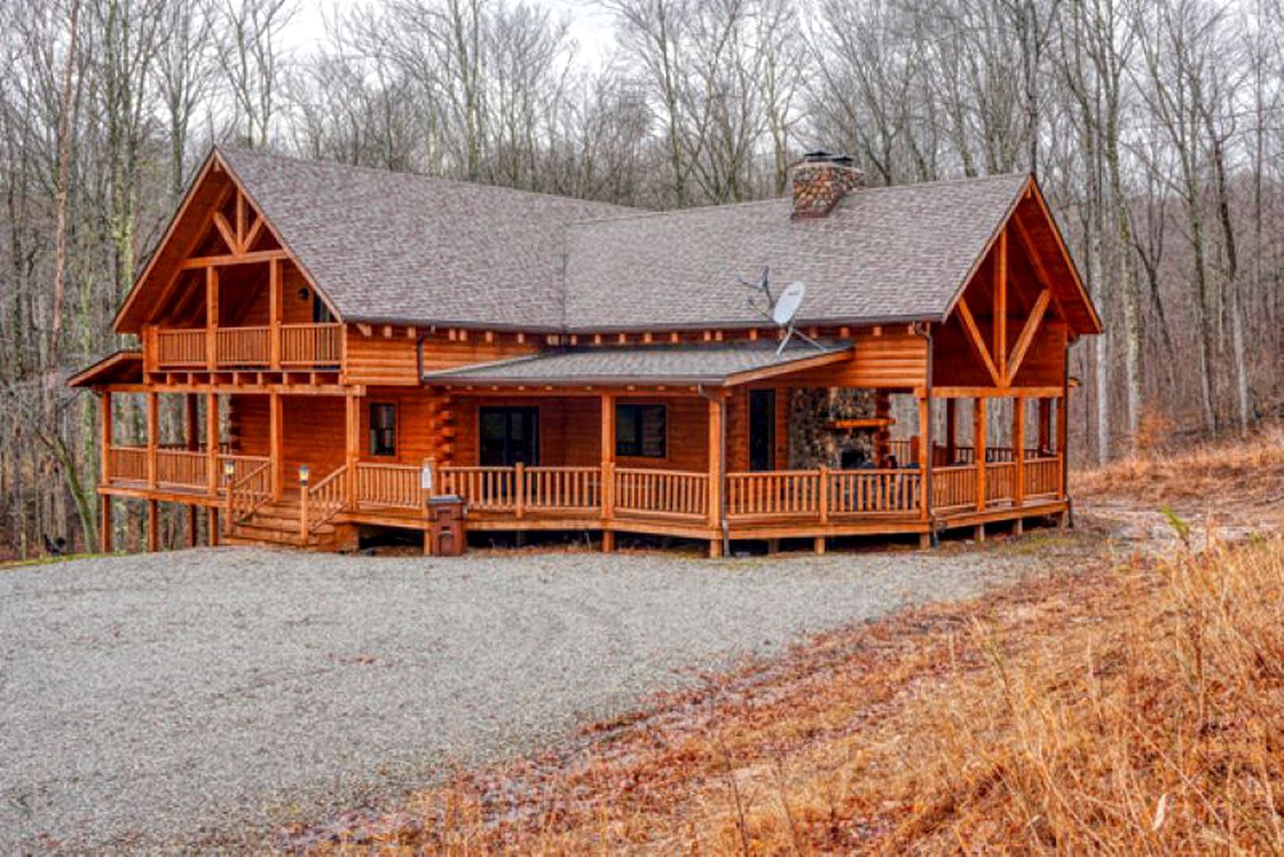 A wooden cabin with a porch, a chimney, and a satellite dish.