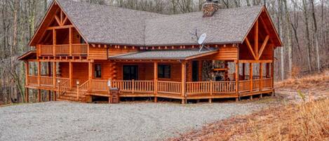A wooden cabin with a porch, a chimney, and a satellite dish.