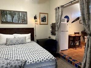 Ein Schlafzimmer mit Bett, Schreibtisch, Stuhl, Kühlschrank und Essecke.