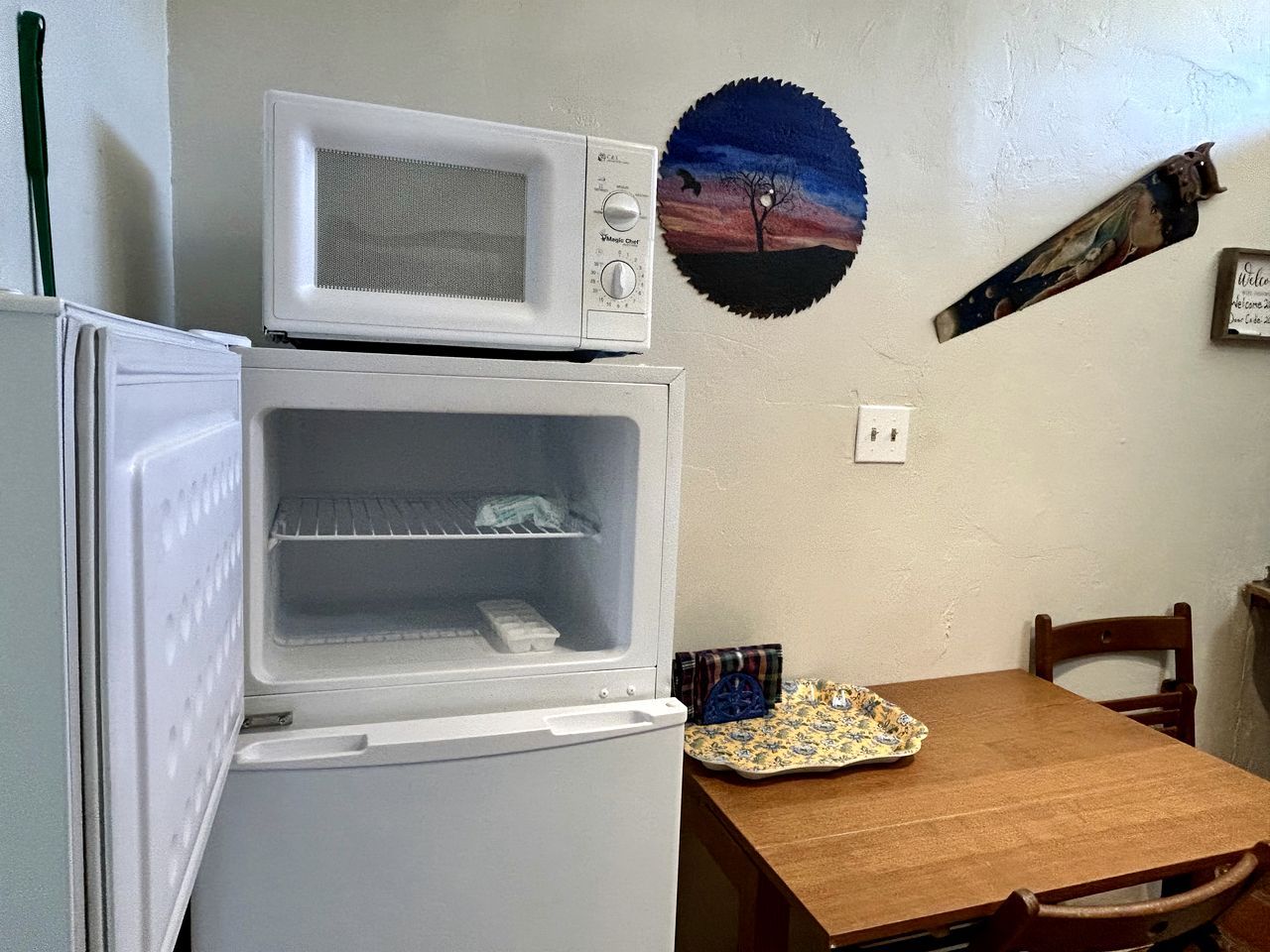 A compact kitchen with a microwave, a mini-fridge, and a dining table.