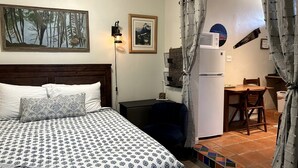 Une chambre comprenant un lit, un bureau, une chaise, un réfrigérateur et un coin repas.