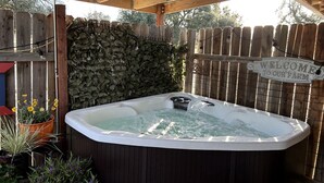 Un bain à remous sous une pergola en bois, avec une pancarte indiquant : « Bienvenue à la ferme ».