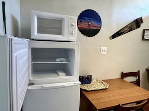 Eine kleine Küche mit Mikrowelle, einem kleinen Kühlschrank und einem Esstisch.