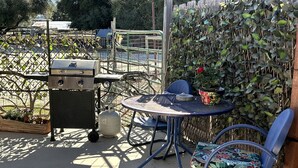 Une terrasse extérieure avec un barbecue, une table et des chaises.