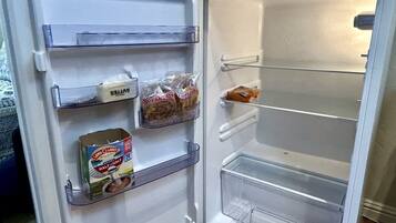 Een open koelkast met planken vol met verschillende soorten eten.