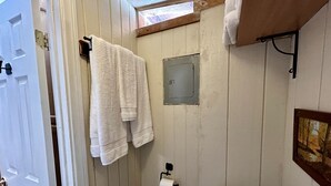 Une salle de bain avec des murs en bois, des toilettes, un porte-serviettes et une fenêtre.