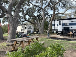 A campsite with a picnic table, RVs, and outdoor furniture.