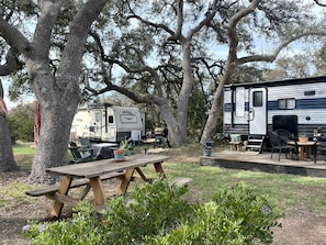 Ein Campingplatz mit Picknicktisch, Wohnmobilen und Gartenmöbeln.
