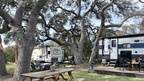 A campsite with a picnic table, RVs, and outdoor furniture.