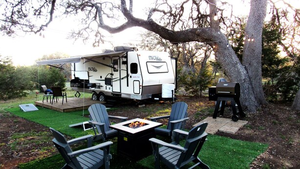 A recreational vehicle with a kitchen area, a fire pit, and outdoor seating.