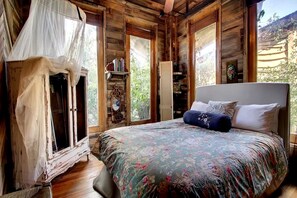 Une chambre à coucher avec un lit, une armoire et une fenêtre donnant sur un paysage verdoyant.